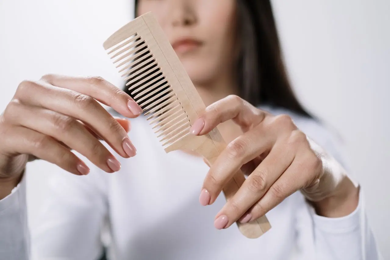 Mujer con un peine de cabello preocupada por la caída capilar